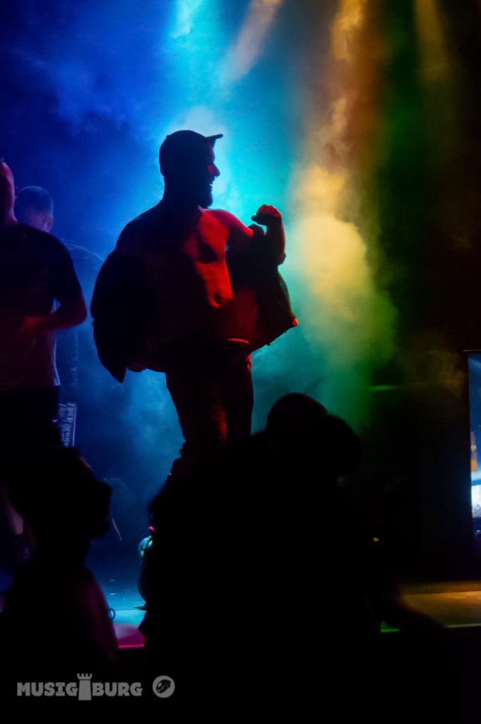 Silhouette eines Djs auf der Bühne mit farbigen Scheinwerfern, die eine dramatische Atmosphäre erzeugen